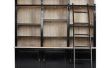 Muur van boekenkasten met een rollende ladder 'on the cheap'
